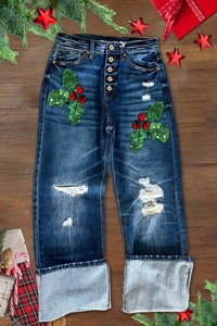 Detail der zerrissenen Jeans mit Pailletten-Stechpalmenblättern und Metallknöpfen