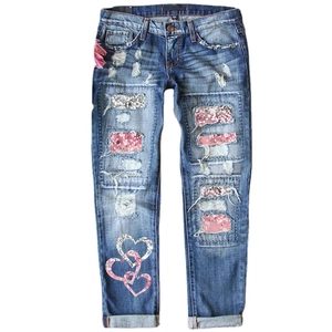 Women's blue distressed jeans with festive red plaid patches and heart sequin details