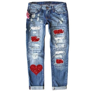 Women's mid-rise distressed blue jeans with red sequin patches and heart embroidery