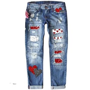 Women's straight-leg blue jeans with red heart patches, distressing, and rolled cuffs