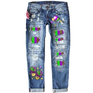 Women's baggy blue distressed jeans with colorful patches and carnival mask print details
