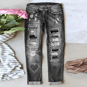 Detail of dark grey distressed jeans with sequin heart patch and frayed rolled hem