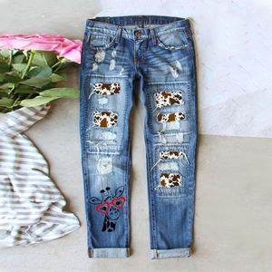 Détail d'un jean bleu délavé avec empiècements imprimé vache et motif girafe
