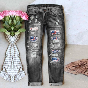 Detailed shot of distressed grey denim jeans featuring American flag patches inside ripped holes