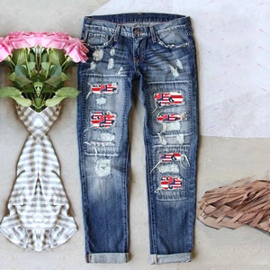 Distressed dark blue straight leg jeans featuring American flag patches and rolled cuffs
