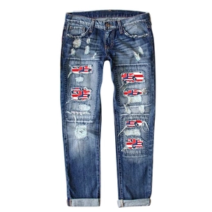 Distressed blue slim jeans with American flag patterns inside ripped holes and cuffed hems