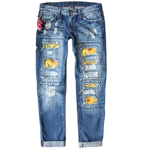 Women's mid-waist ripped jeans featuring sunflower print patches and cuffed hems