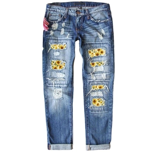Women's light blue ripped jeans featuring sunflower print patches and pink floral waist accent