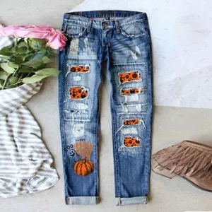 Detail of ripped jeans featuring Halloween pumpkin prints and cat patterns inside holes
