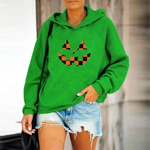 Detail of ripped blue denim shorts paired with a bright green pumpkin print hoodie