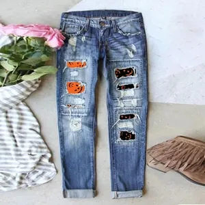 Detail of ripped blue jeans featuring festive Halloween pumpkin and black cat inner patches