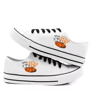 Detail of white low-top canvas shoes with festive Halloween pumpkin and ghost patterns