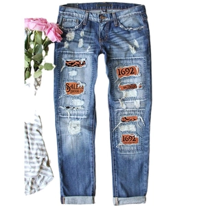 Distressed dark blue straight jeans with vintage Salem Halloween themed patches