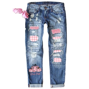 Women's blue ripped jeans featuring pink sequin patches and pumpkin print for Halloween