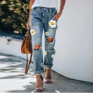 Detail of light blue denim jeans with sunflower prints, drawstring waist and cargo pockets