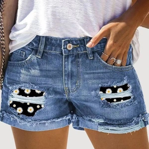 Détail du short en jean bleu avec imprimé marguerites dans les déchirures et bords effilochés