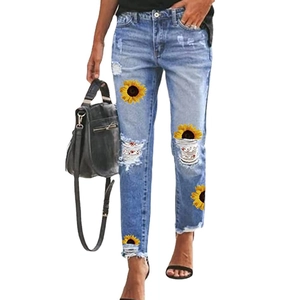 Women's light blue distressed jeans with sunflower print and ripped detailing in slim fit
