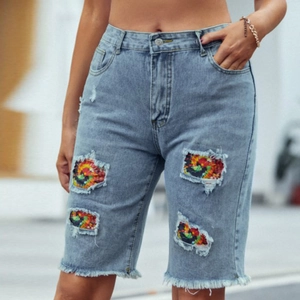 Détail du short en jean bleu clair avec doublure tie-dye colorée dans les trous déchirés