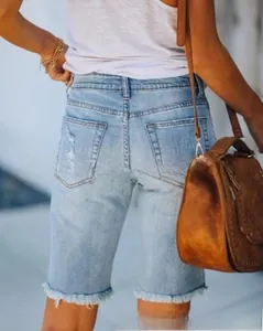 Détail du bermuda en jean bleu clair avec ourlet effiloché et texture de la poche arrière