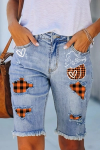 Detail of light blue denim shorts with orange plaid patches and wizard hat embroidery