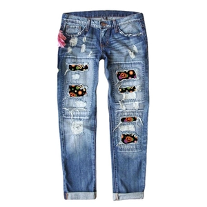 Women's blue ripped jeans with Halloween pumpkin and skull print patches, cropped fit