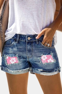 Détails de short en jean délavé avec empiècements fleuris et bords francs effilochés