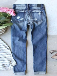 Women's dark blue straight-leg distressed jeans with rose decor on gray background