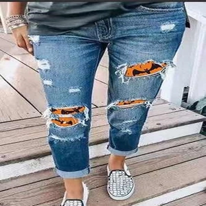 Women's blue distressed ripped jeans featuring Halloween pumpkin and bat pattern inserts