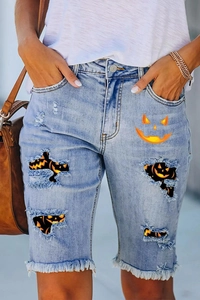 Detail of distressed denim shorts with Halloween pumpkin prints and frayed hems