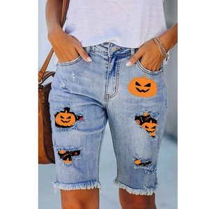 Detail of distressed light blue denim shorts with pumpkin prints and frayed hems
