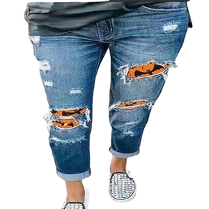 Women distressed blue denim jeans with Halloween pumpkin and bat patterns inside rips