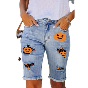 Women's light blue denim shorts with Halloween pumpkin print and frayed hem detail