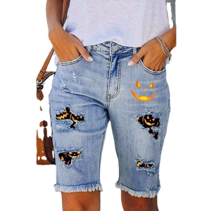 Women's blue denim shorts with Halloween pumpkin prints and distressed fringe hems