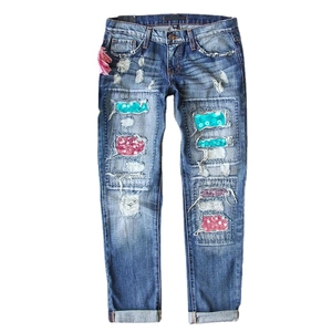 Women's blue denim jeans with ripped leopard print sequins and a pink silk flower detail