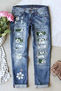 Detail of distressed blue jeans with floral patchwork inserts and printed flower graphic