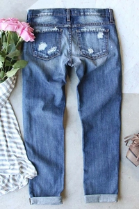 Detail of distressed ripped denim jeans with vintage wash and back pocket patch work