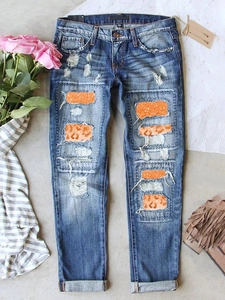 Jean bleu délavé avec empiècements imprimé léopard et détails à paillettes orange