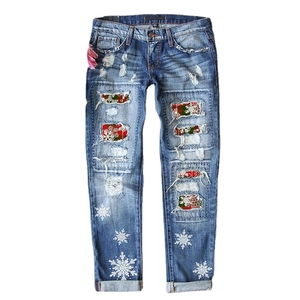 Women's blue denim jeans with Christmas snowflake patches and distressed ripped details