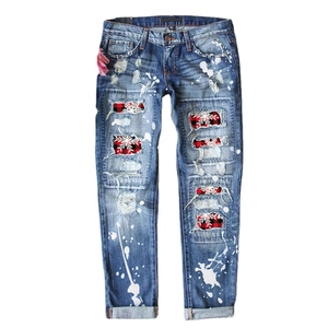 Women's slim blue jeans with paint splatters, distressed holes, and red plaid snowflake patches