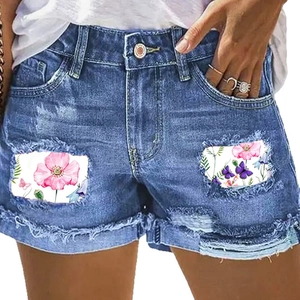 Pantaloncini in denim blu vintage da donna con toppe floreali, strappi e orli sfilacciati