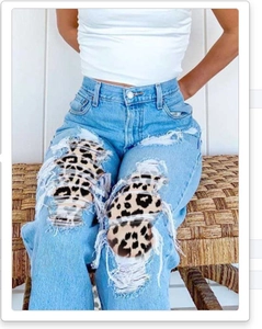 Détail d'un jean taille haute bleu avec genoux déchirés et empiècement imprimé léopard