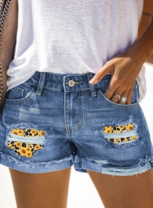 Détail du short en jean bleu avec patchs imprimé léopard et tournesol et bords effilochés