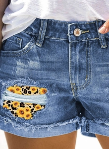 Gros plan d'un short en jean taille haute avec écussons tournesol léopard et franges