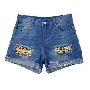 Détail du short en jean bleu avec patchs tournesol léopard et finitions effilochées