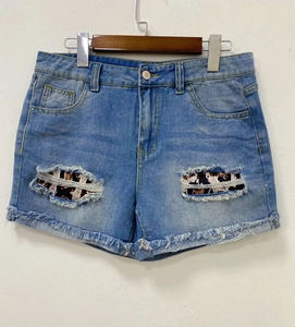 Detail of light blue denim shorts featuring ripped holes with leopard print fabric inlay