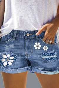 Detail of denim shorts with leopard print patchwork and white daisy flower prints