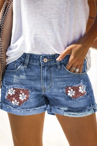 Women's blue denim shorts with leopard floral patches and distressed frayed hems