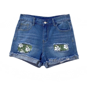 Distressed blue denim shorts with floral daisy patch inserts and frayed hem details