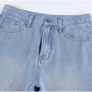 Detail view of light blue denim waist featuring metal button and zipper fly closure
