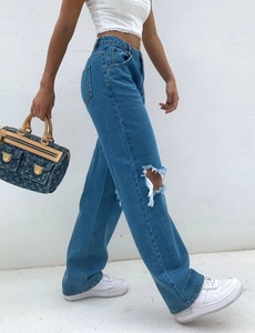 Gros plan sur un jean en denim bleu à taille haute avec des détails déchirés aux genoux